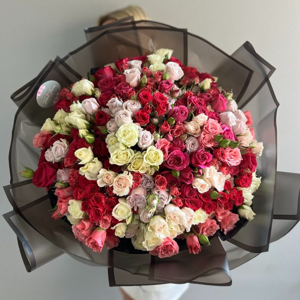 Spring Fling bouquet with 150 roses in soft pink, white and red tones in black wrap