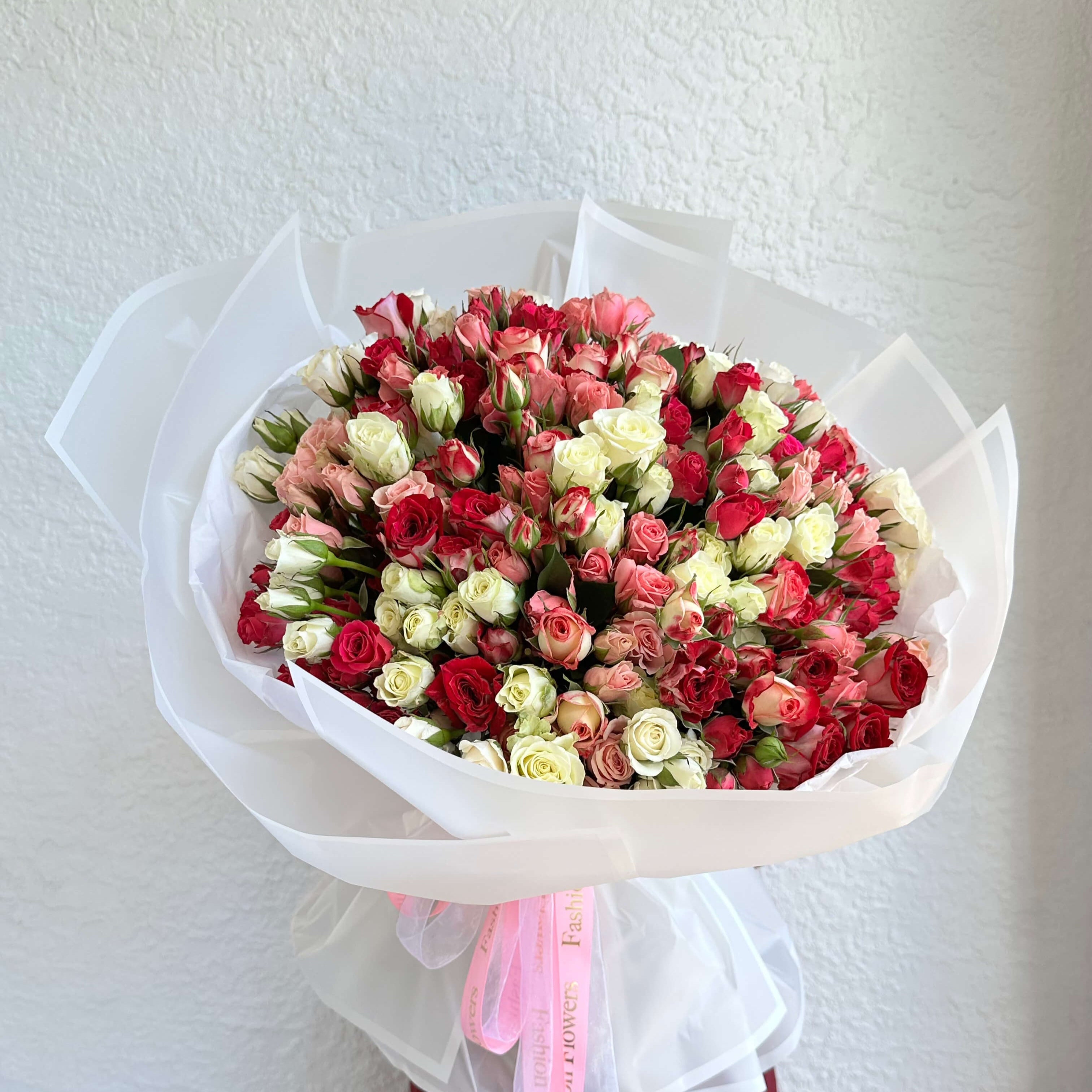 Spring Fling bouquet with 150 roses in soft pink, white and red tones in white wrap