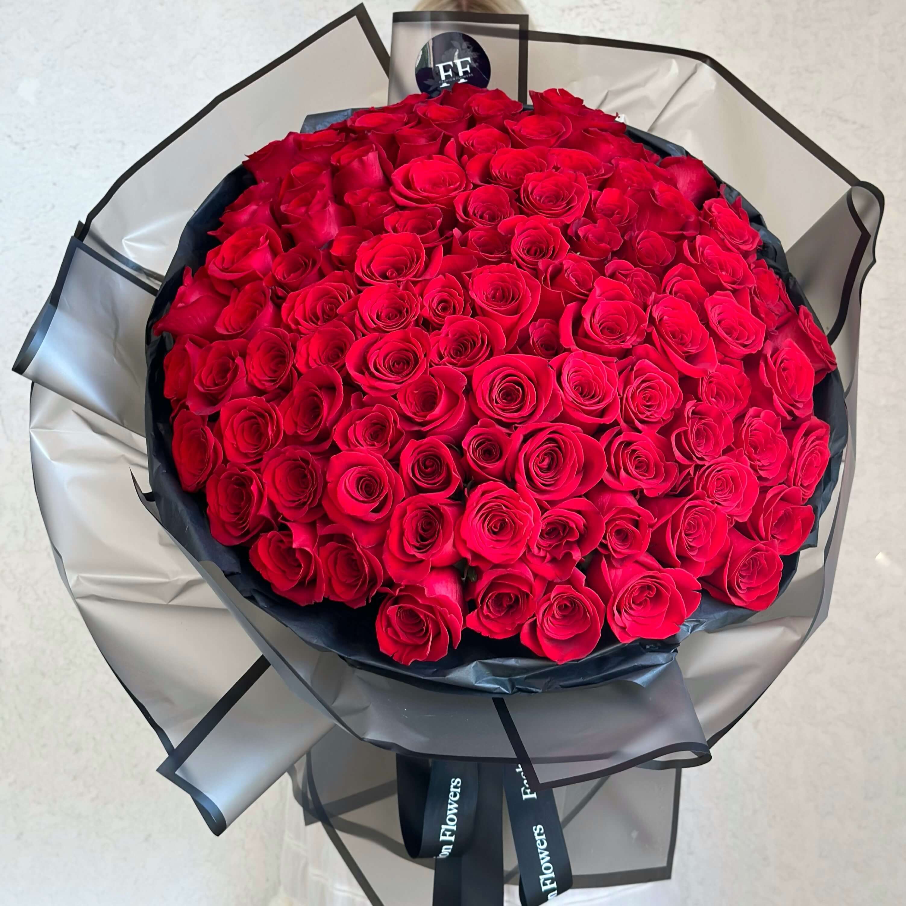 Hand-tied bouquet of over 200 small red roses in black wrap â luxury flower delivery