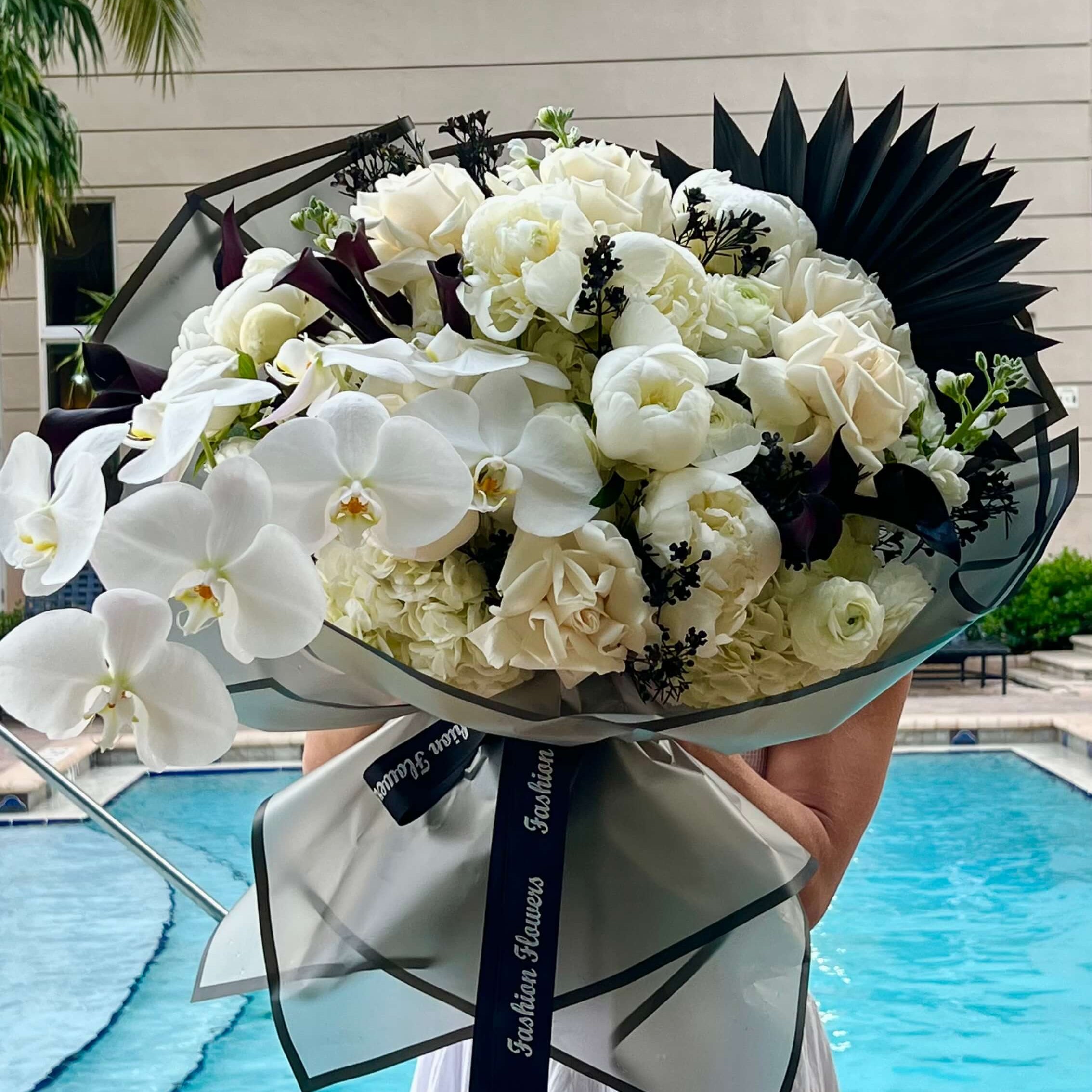 Day and Night bouquet with white orchids and roses — luxury flower delivery Miami by the pool at modern villa