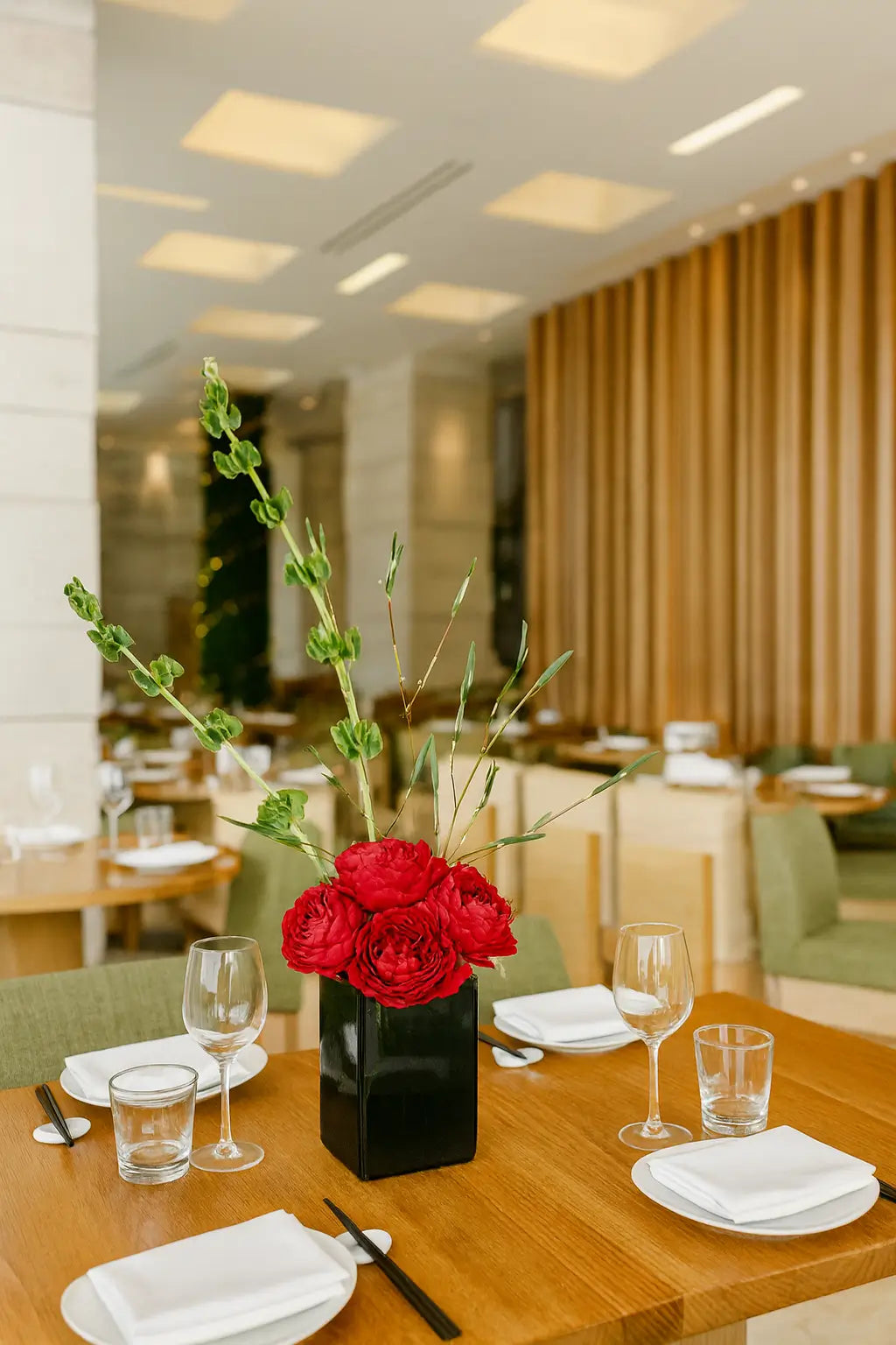 An elegant daytime view of the Zuma Miami dining area with natural light filling the high-ceilinged space, wooden tables set with fine glassware and plates, and a warm yet sophisticated ambiance.