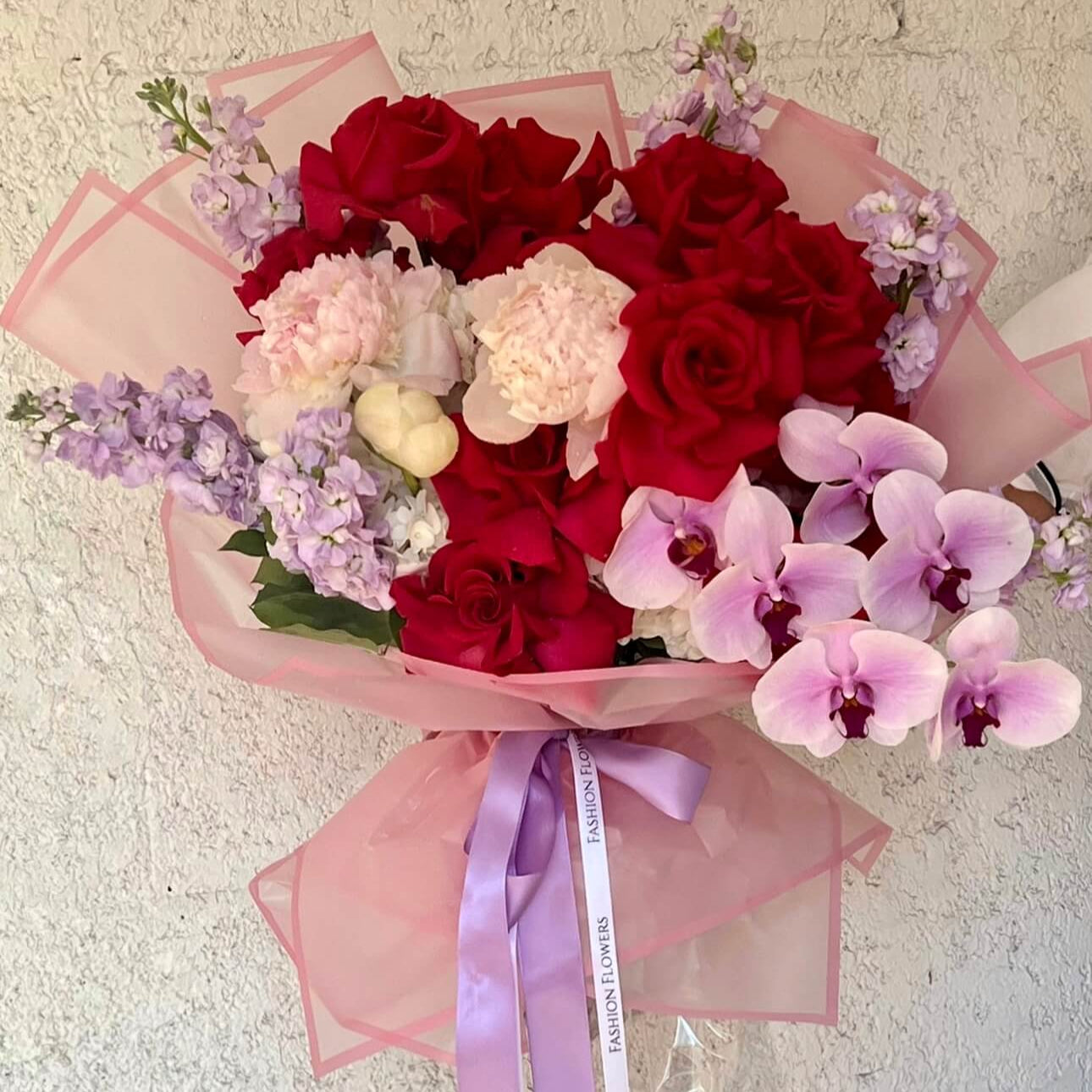 Fusion of Passion hand-tied bouquet with red roses, orchids, and pink peonies — luxury flower delivery Miami
