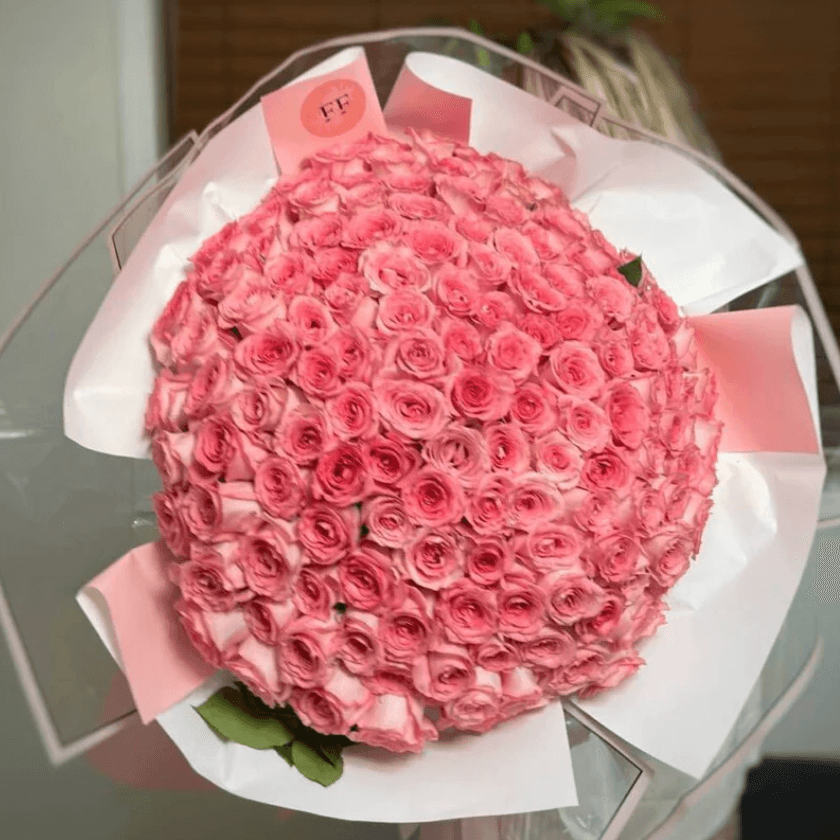Elegant bouquet of 100 pink roses with transparent and pink wrapping — luxury same-day flower delivery