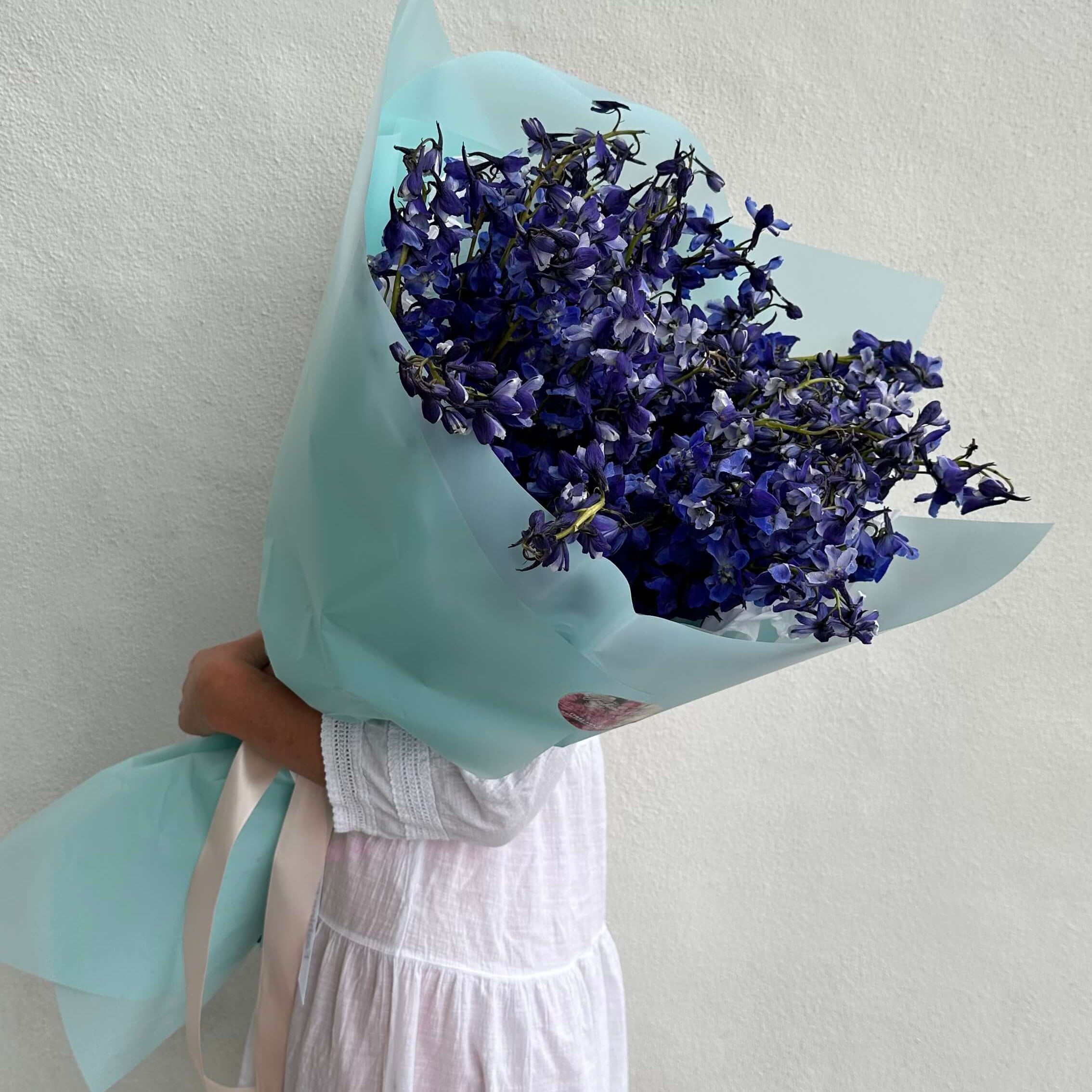Just Blue bouquet with long delphiniums in cool blue wrapping — elegant hand-tied flower gift Miami