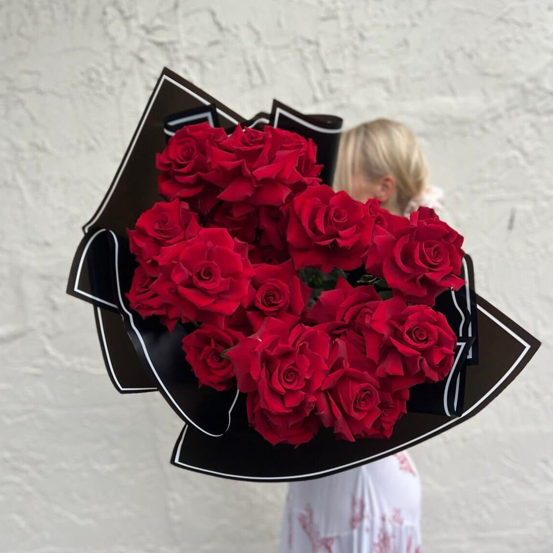 My Valentine bouquet of classic red roses in black luxury wrap â held by smiling blonde woman, Miami delivery