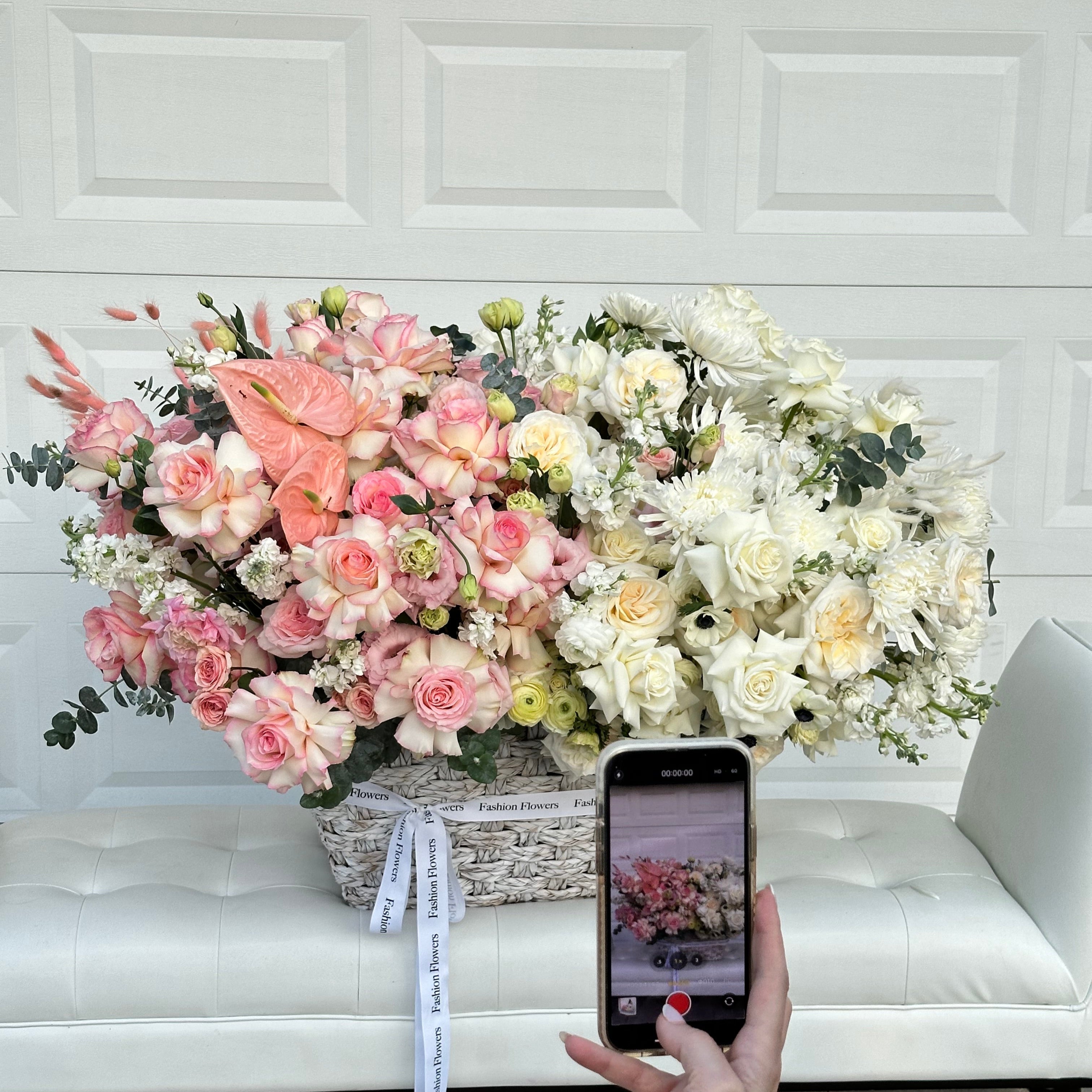 Ocean of Love large flower basket with pastel roses and carnations on a yacht table beside smiling blonde woman â Miami
