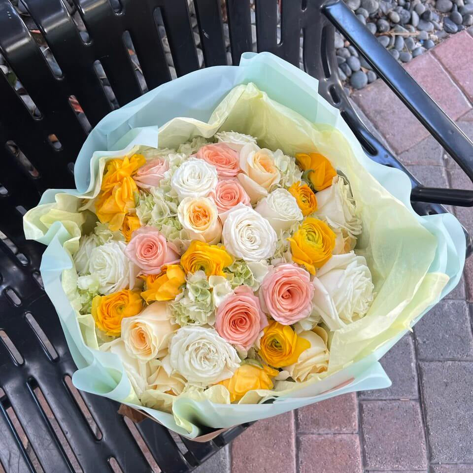 Peaches and Creamsicle bouquet with yellow ranunculus and roses in pistachio wrap — flower delivery Miami