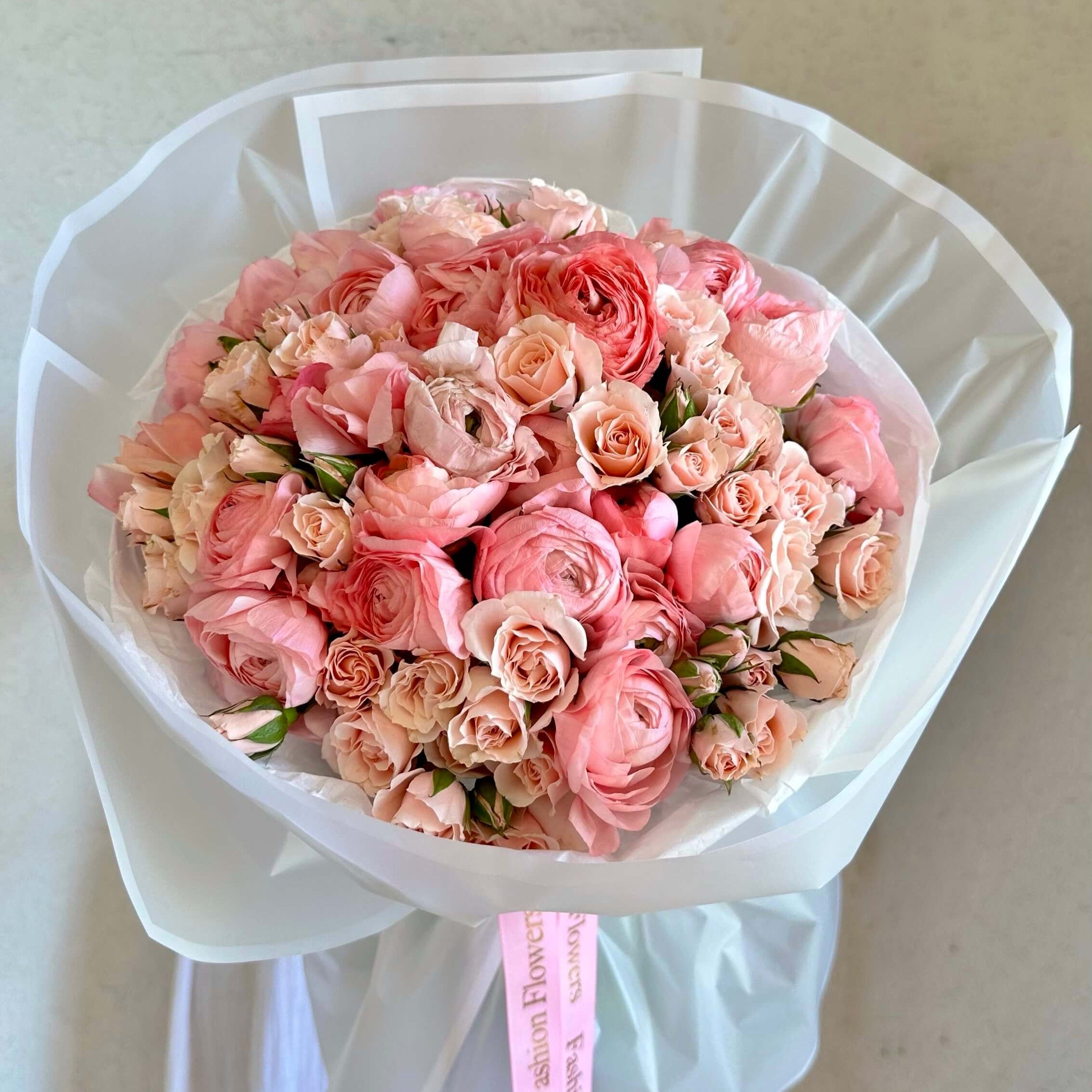 Pink bouquet of 100 roses and ranunculus wrapped in sheer white paper — luxury flower delivery in Miami marina
