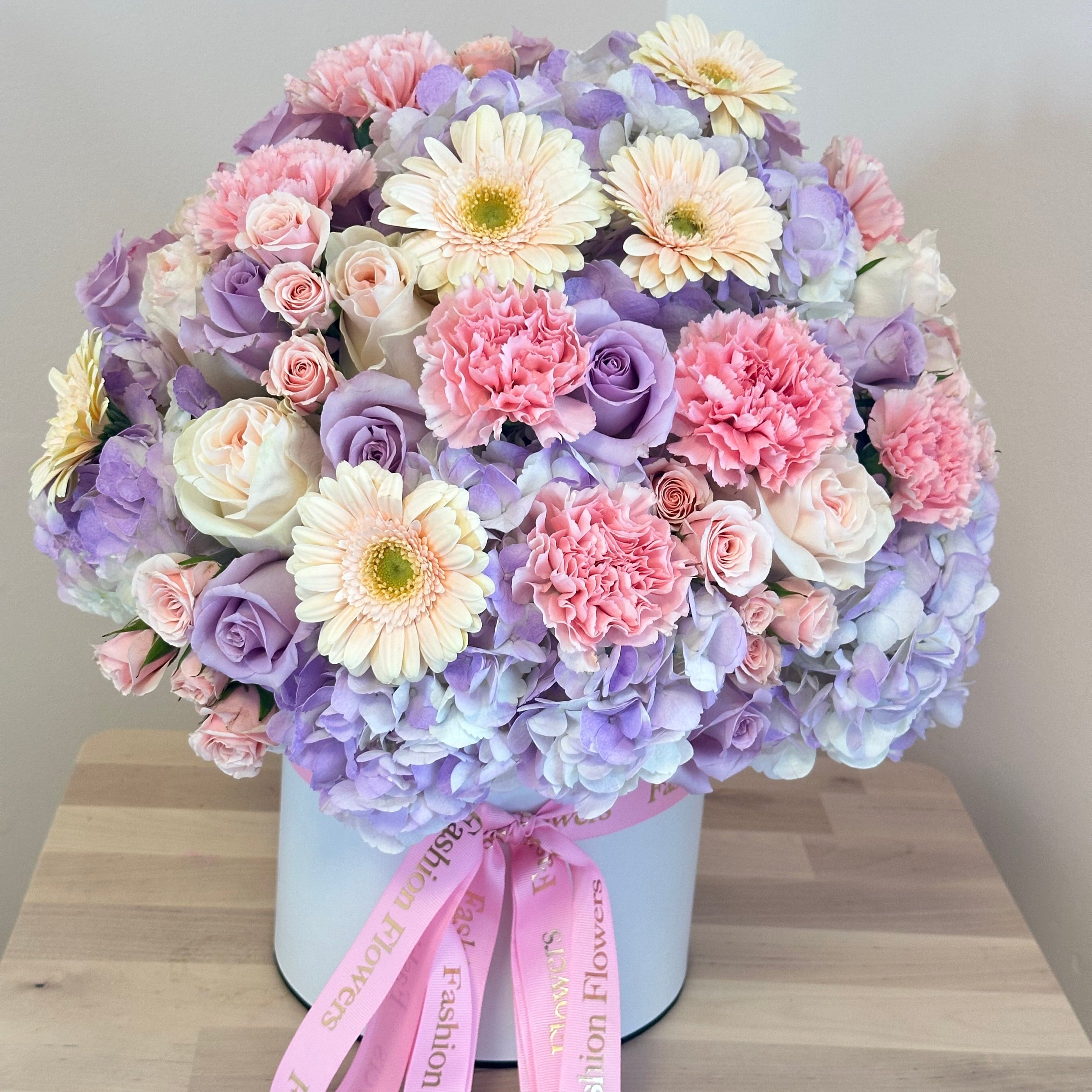 Purple paradise bouquet with lavender roses and carnations in a white designer box — luxury flower delivery Miami balcony