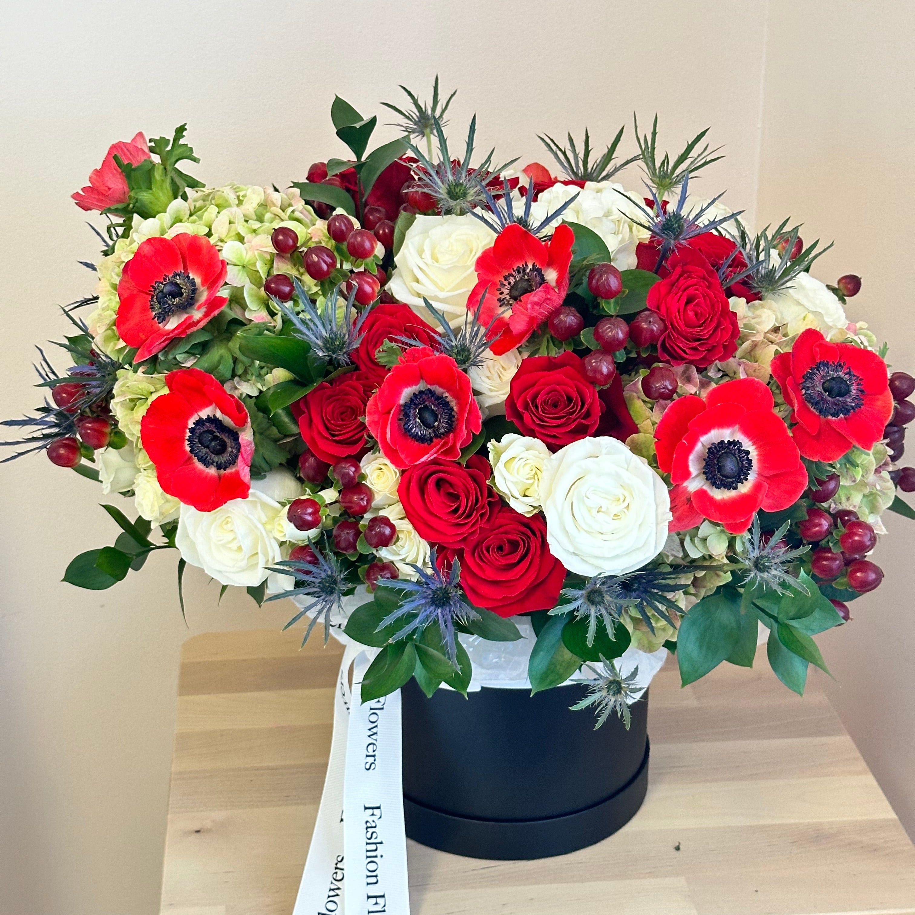 Red forest floral bouquet with anemones and berries in a black luxury box â held by woman in Miami tropical garden