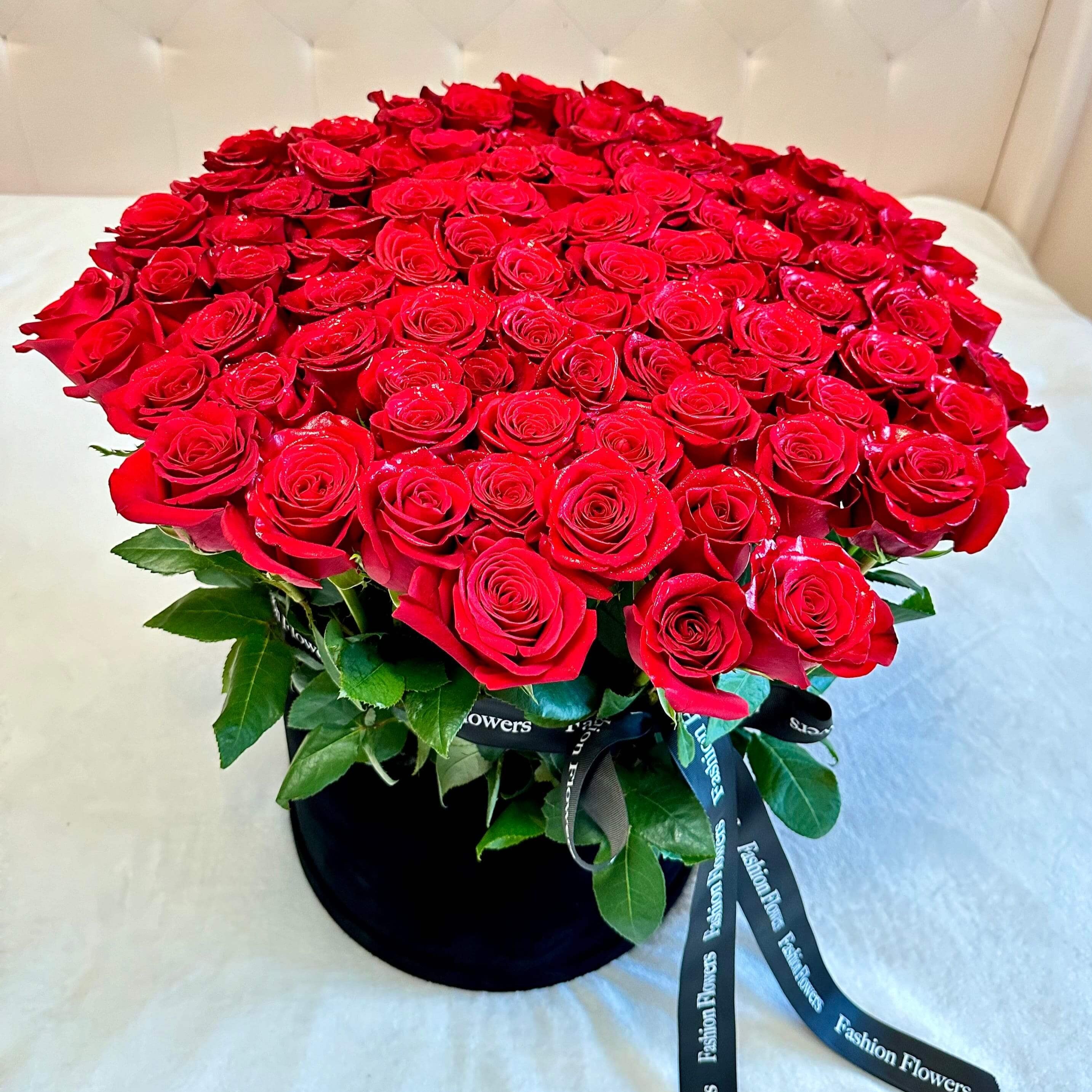 Red roses in box â 100 long stem roses in black velvet box held by woman on marina terrace â luxury flower gift Miami