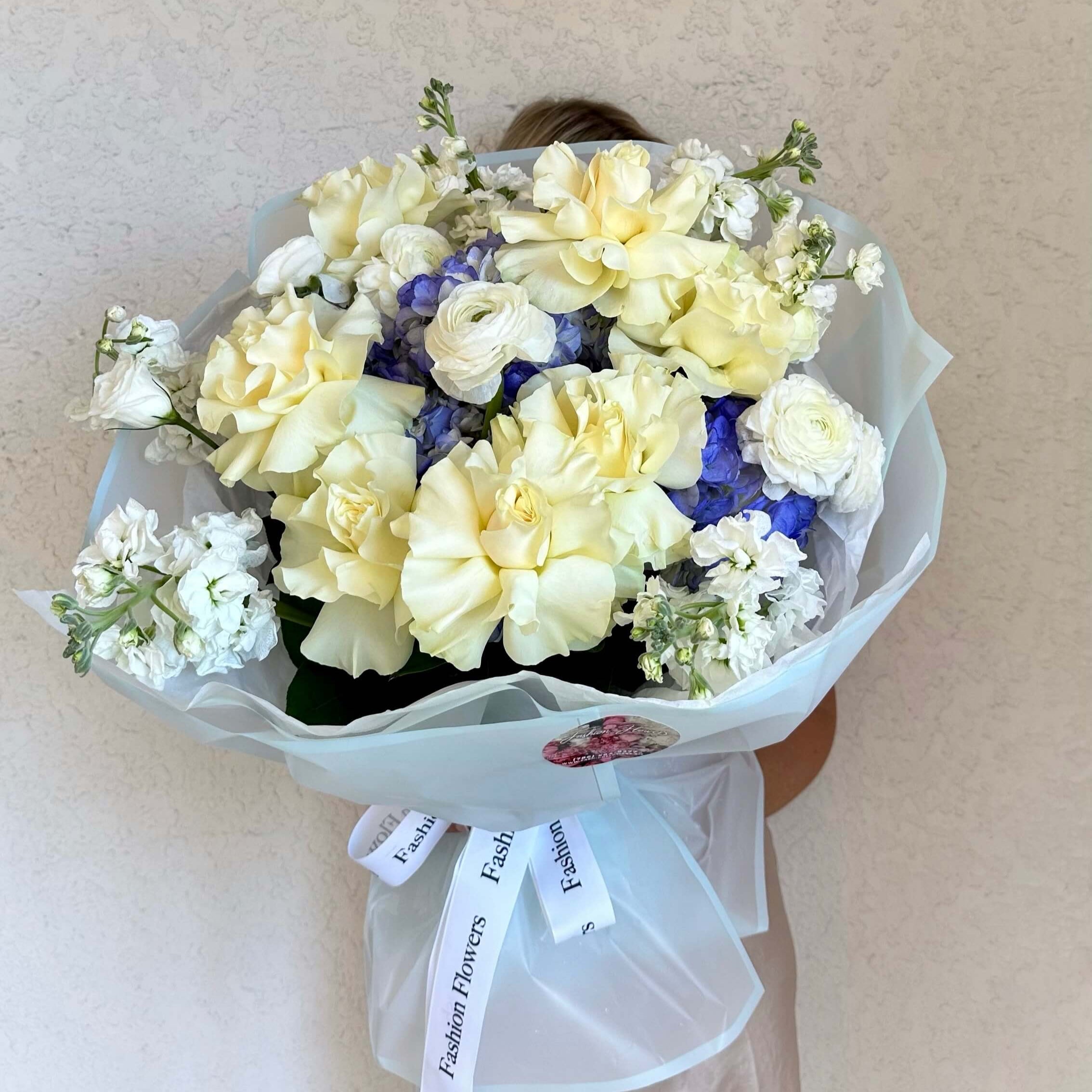 Waves of Tenderness bouquet with white roses and blue hydrangeas in sheer white wrap — luxury flower delivery for elegant moments