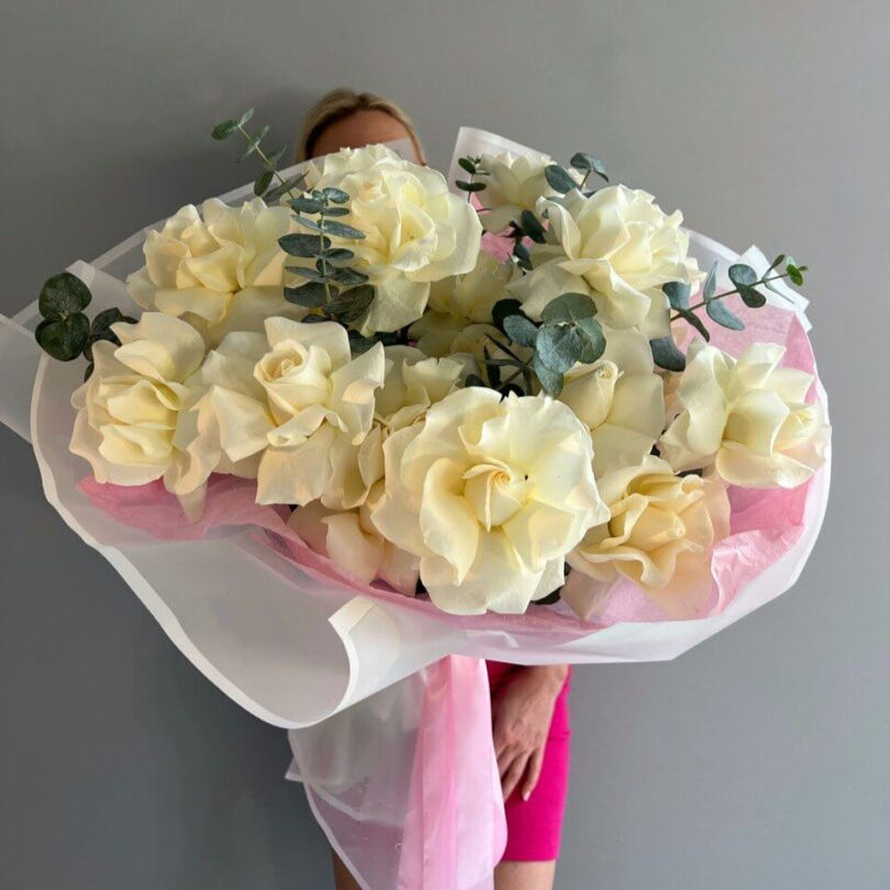 Hand-tied bouquet of white roses and eucalyptus in white wrapping — elegant flower gift Miami