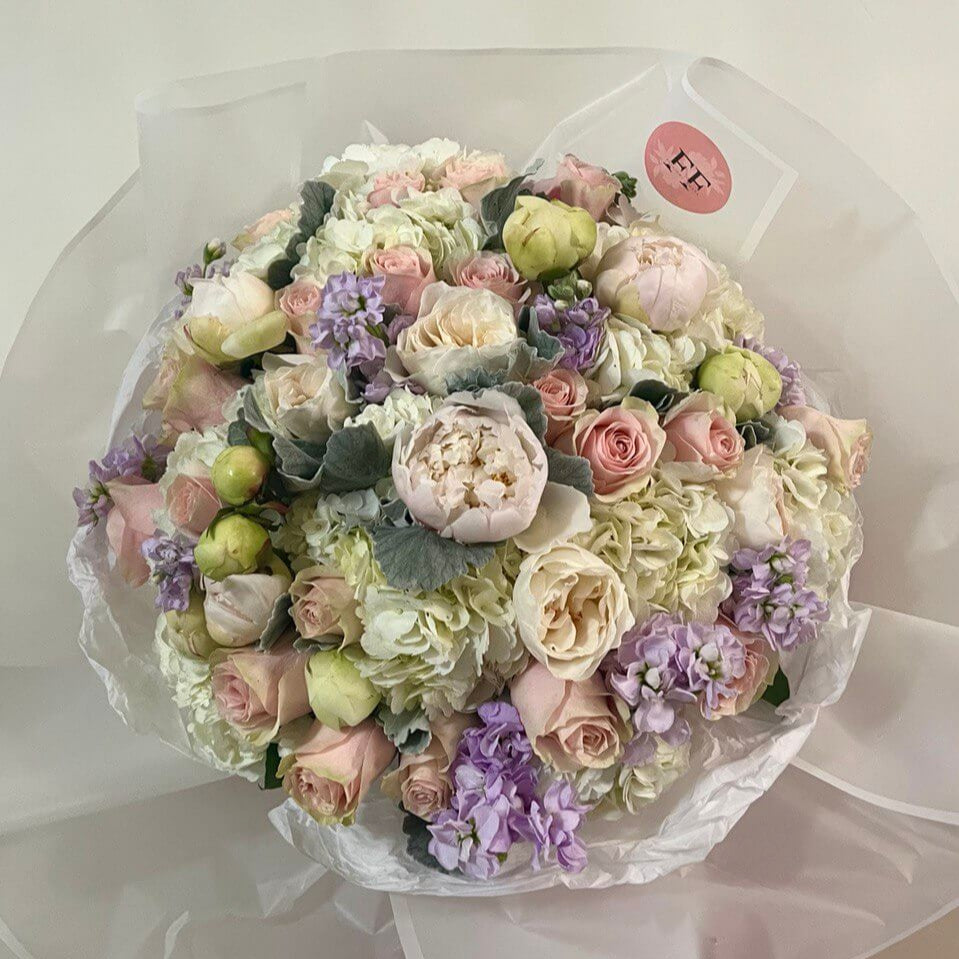 Elegant pastel bouquet of roses, peonies, hydrangeas wrapped in white — romantic luxury flower delivery