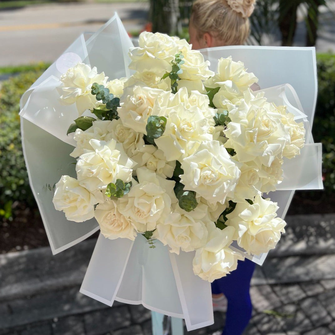 Double white rose bouquet in luxury wrapping held by sporty woman â same-day flower delivery Miami