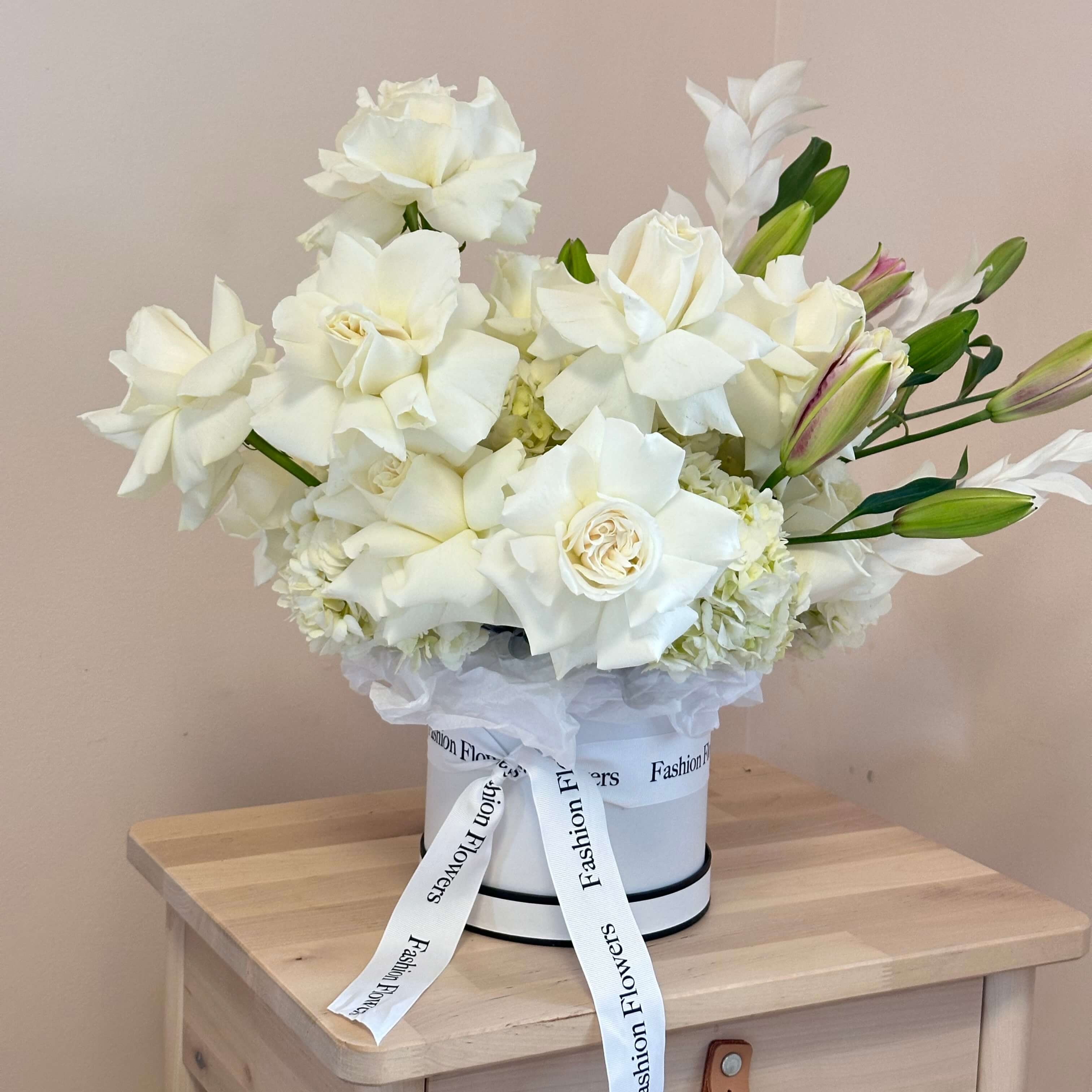 Elegant white box with roses, hydrangeas, and lilies in a luxury suite — romantic flower delivery Miami