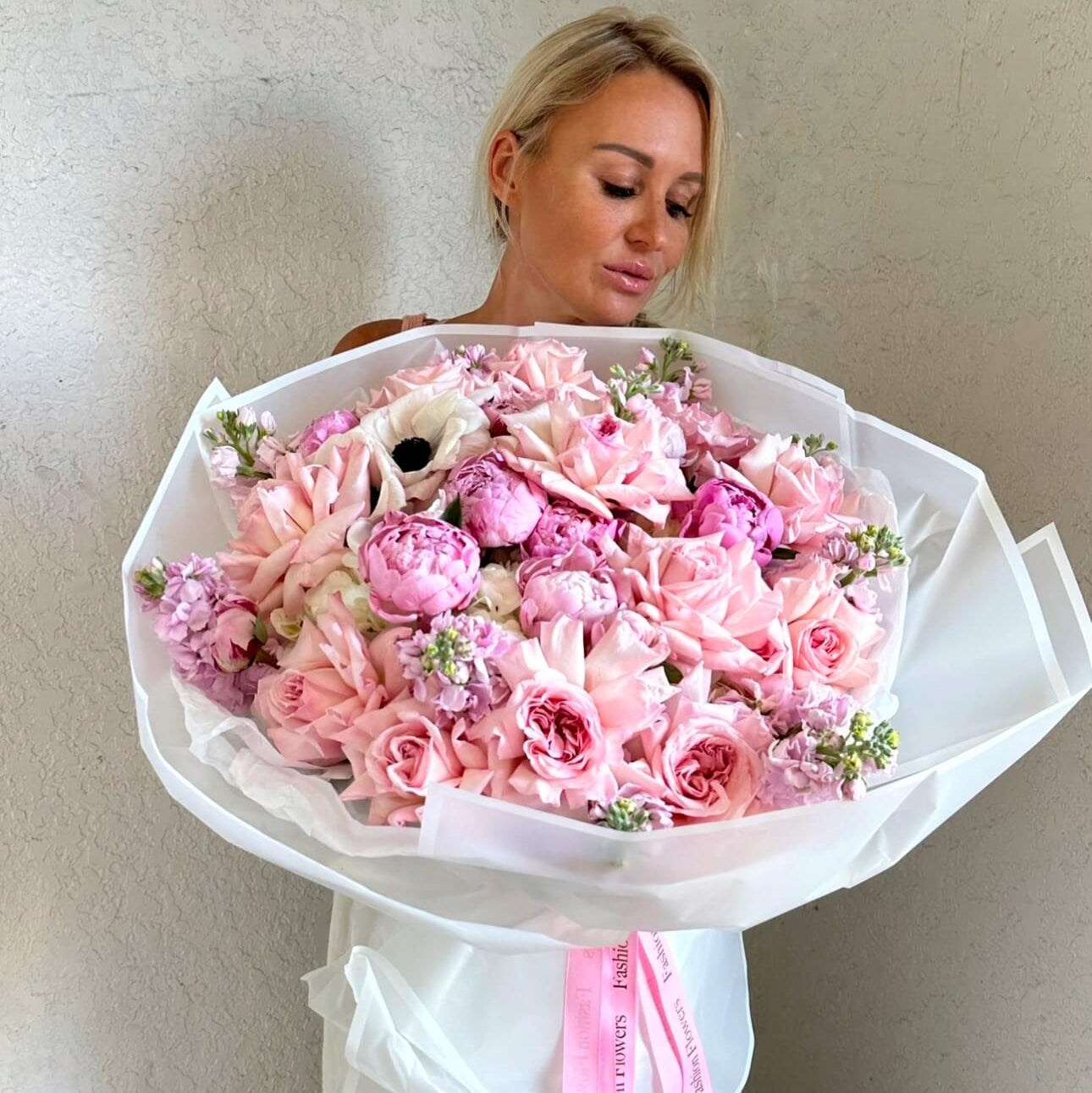 A luxurious hand-tied bouquet in soft pink tones with delicate peonies and roses, perfect for romantic surprises.