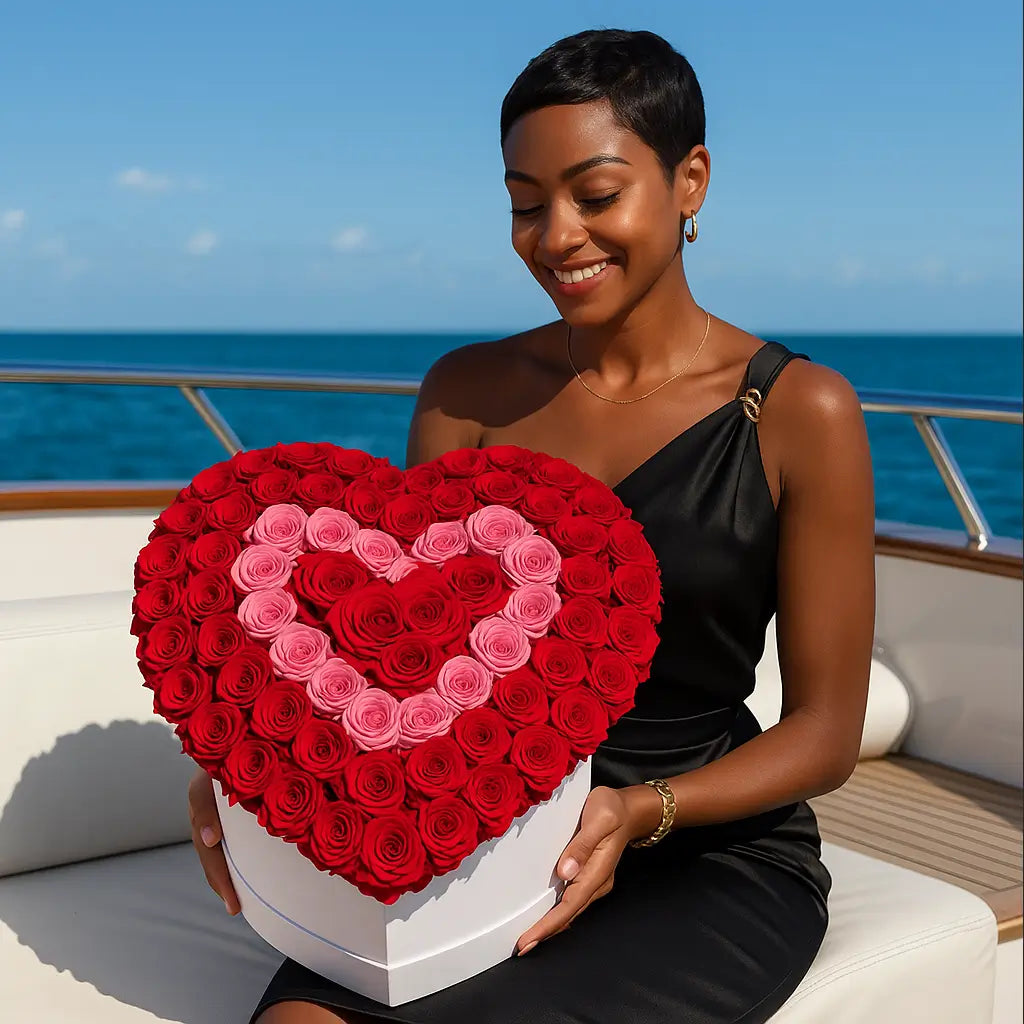 Heart-shaped box with 200 red and pink roses on a yacht table — elegant bouquet held by smiling woman at sea