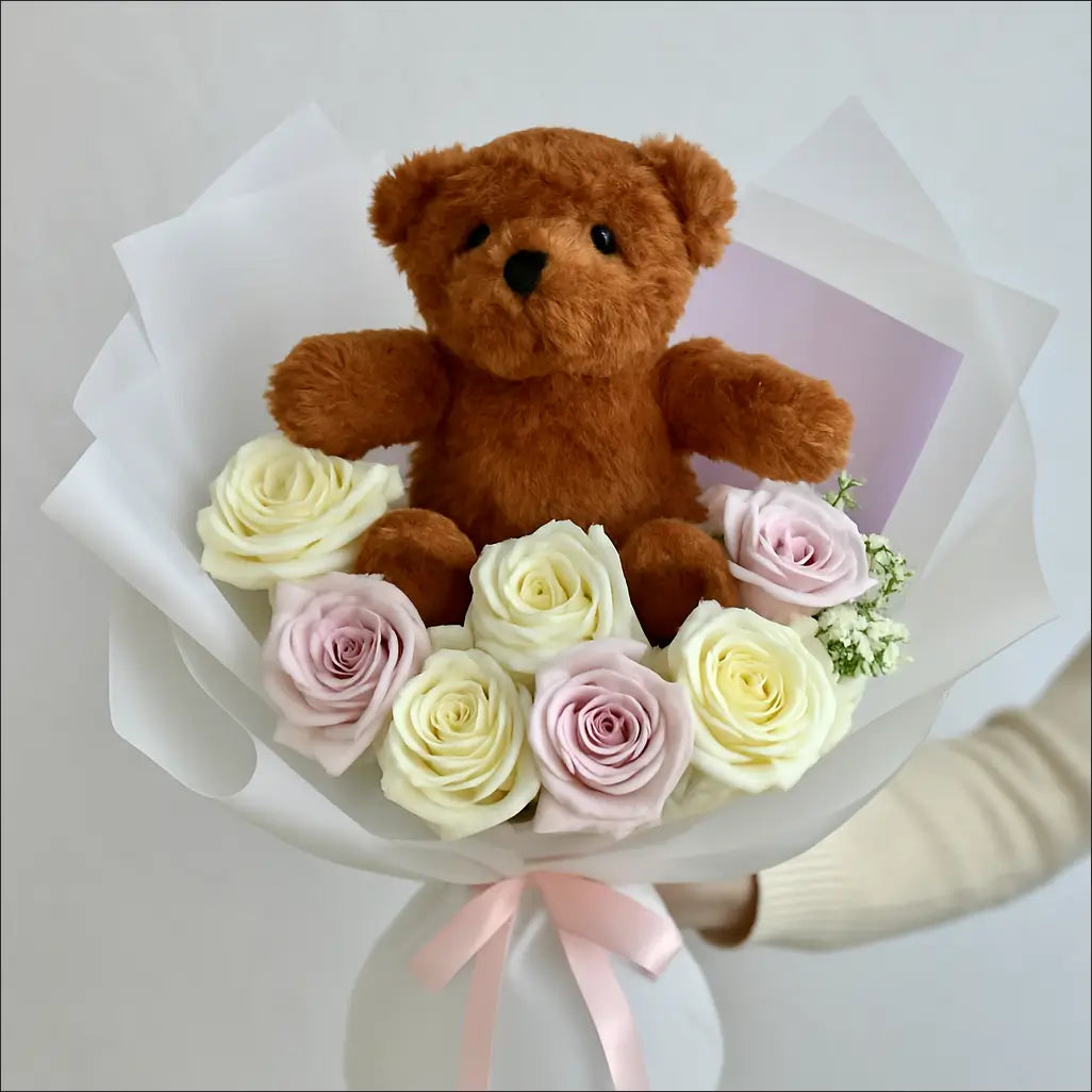 Hand-tied bouquet with roses and a plush brown teddy bear — romantic gift for any occasion