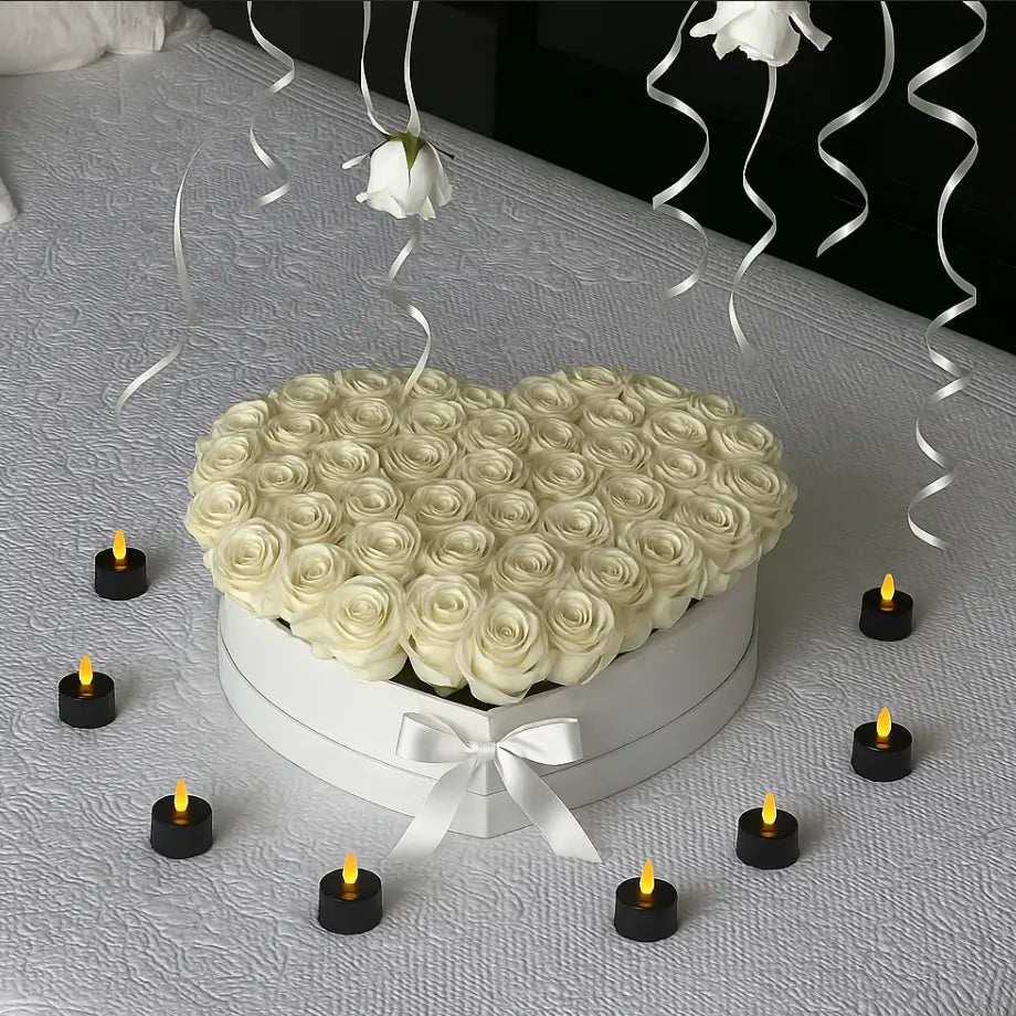 Heart-shaped designer box with white roses and candles on elegant bed — luxury flower delivery in Miami