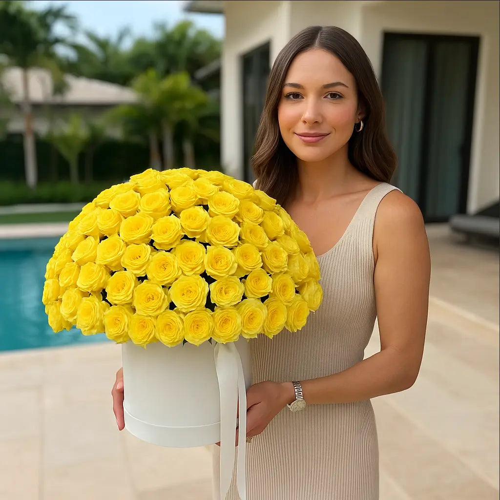 Large white box of yellow roses held by woman on poolside villa patio — elegant flower delivery Miami